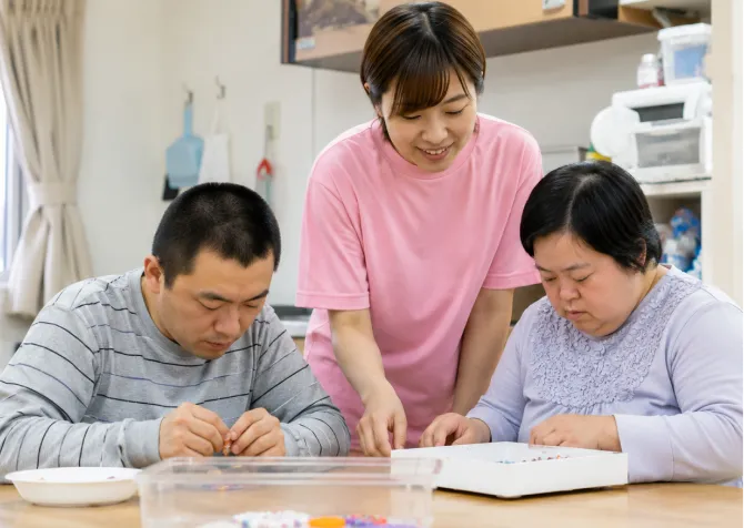 机に向かう利用者を見守る職員