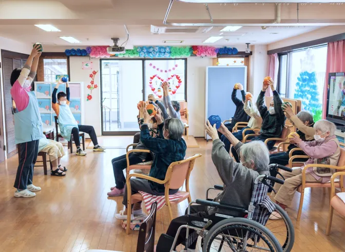 室内で手を上げて体操する利用者たち